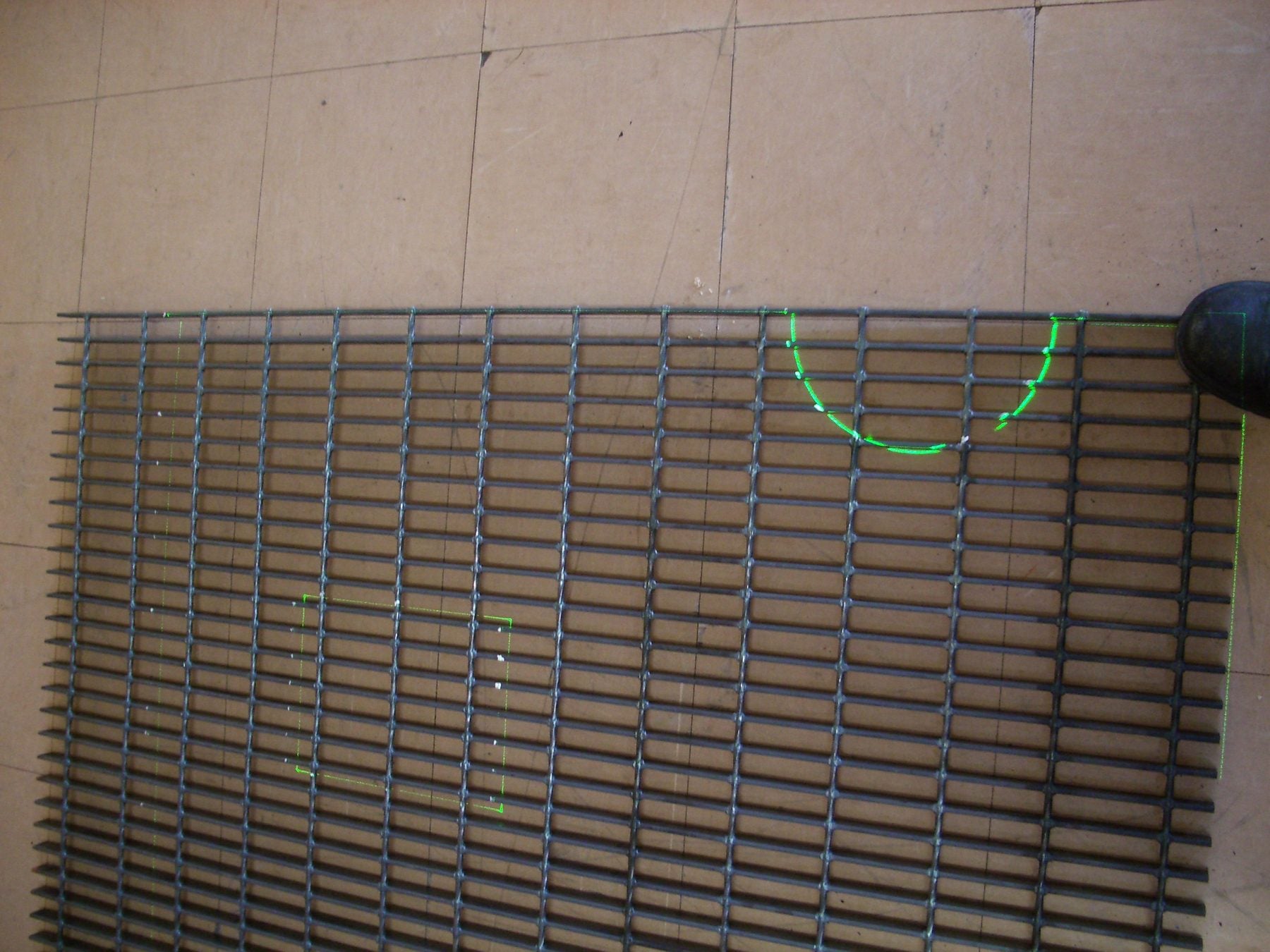 Steel plate on a welding bed with green laser lines marking fit-up positions and hole centres